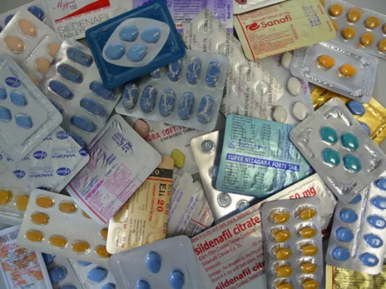 Pillole di Viagra blu su un tavolo con un flacone di farmacia e un conto salato